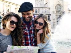 young adults smiling, looking at map with fountain behind them