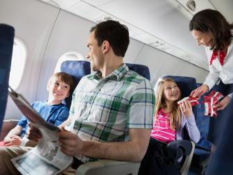 Flight attendant handing out snacks to family in airplane